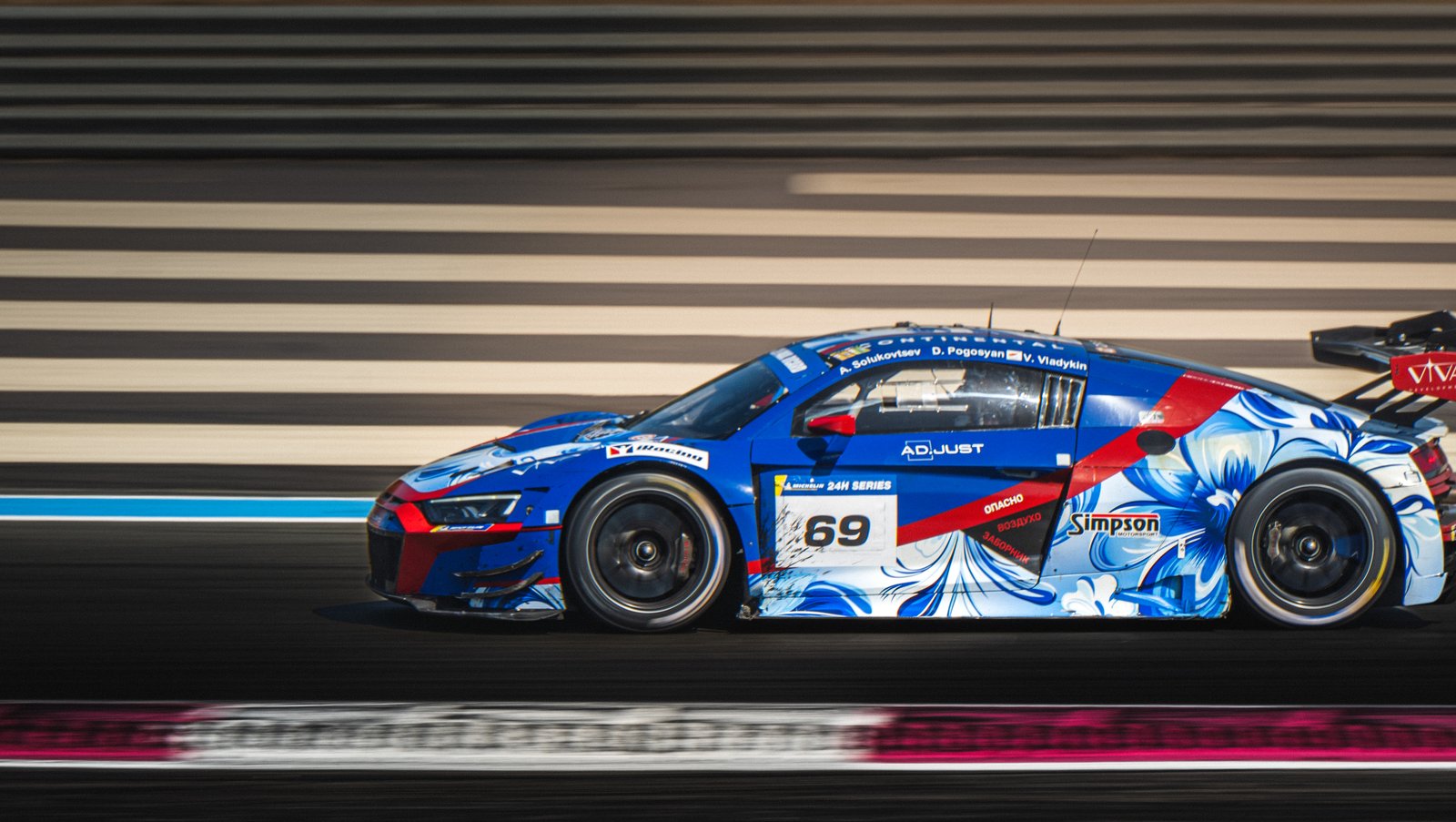 Audi R8 de course bleue et blanche en vitesse sur piste